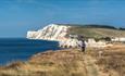 Walker along the cliff at Freshwater Bay with Freshwater Bay House in the background, walking holiday, Isle of Wight