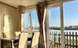 Dining area inside a caravan with a view of Bembridge Harbour at Old Mill Holiday Park, Isle of Wight