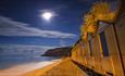 Night time view with the moon shining over the beach huts at Shanklln beach, Things to Do, Isle of Wight