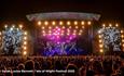 Crowds watching a band on the main stage in the evening at the Isle of Wight Festival, music event, what's on