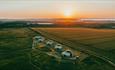 Aerial view of Dome Meadow with the sunset over the sea, Tom's Eco Lodge, Tapnell Farm Holiday Destination, self-catering, West Wight, Isle of Wight