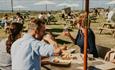 Friends dining on the lawn outside of The Cow Restaurant, Food & Drink, Tapnell Farm Park, Isle of Wight