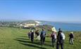 Group of walkers walking down Tennyson towards Freshwater Bay House, walking holiday, Isle of Wight