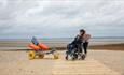 Boy in wheelchair with mother on the boardwalk next to a beach wheelchair at Ryde beach, Isle of Wight, Things to Do, accessible beach