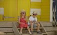 Children sitting on beach hut steps at Colwell beach near The Bay Colwell Holiday Resort, Isle of Wight, Self Catering