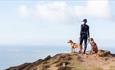 Two dogs with their owner on the cliff at Compton looking out to sea, Trotting Dog, Isle of Wight, activities, walking, running, dog-friendly trails