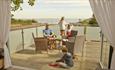 Family enjoying outside dining area on balcony of self catering cottage with sea views at The Bay Colwell Holiday Resort, Isle of Wight