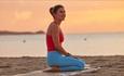 Lady sitting on yoga mat on the beach, Joyride Festival, Isle of Wight, cycling, wellness, health & wellbeing, food, music, what's on, event