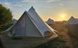 Outside view of bell tents with sunset in the background at Warren Hill Camp with sunset in the background, glamping, accommodation, camping, Isle of