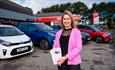 Lady with leaflets on the showroom court with a selection of cars available to hire at Leslies Kia Rental, car hire, Isle of Wight