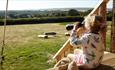 Girl sitting on porch looking out with binoculars from safari tent, Glamping the Wight Way, self catering, Isle of Wight