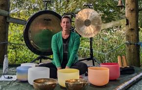 Mel sitting with bowls and gongs to provide a sound bath in the forest on the Isle of Wight, wellness, retreat, activity, health and wellbeing, sanctu