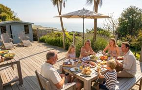 Family eating outside on terrace with sea in the background at Gills Cliff House in Ventnor on the Isle of Wight, self catering