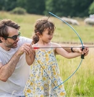 Father helping daughter with archery, National Trust event, Newtown National Nature Reserve, events, what's on, Isle of Wight - photo credit: David Ki