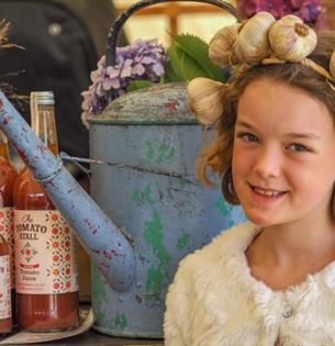 Girl with a garlic head band on standing next to local produce at the Isle of Wight Garlic Festival, what's on, event, Newchurch