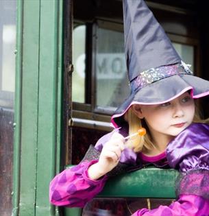 Girl dressed up as a witch looking out of the carriage window at the Wizard Week event, Isle of Wight Steam Railway, what's on