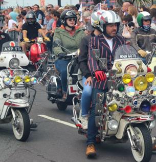 Isle of Wight Scooter Rally, image of Scooter Riders riding along road with onlookers applauding