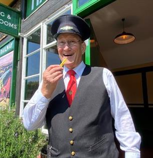 Conductor eating a chip at the Fish and Chip Evenings at Isle of Wight Steam Railway, Wootton, summer event