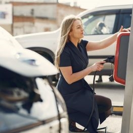 Woman using electric vehicle charging point