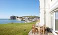 Outside patio with dining chairs and table with views across Freshwater Bay, Bay View, self catering
