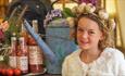 A girl wearing a garlic headband standing next to local produce at the Isle of Wight Garlic Festival, what's on, event