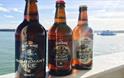 Three bottles of beer on ledge overlooking solent with ferry in background, Isle of Wight, Local Produce, Island Brewery, let's buy local