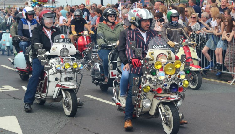 Isle of Wight Scooter Rally, image of Scooter Riders riding along road with onlookers applauding