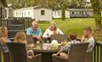 Family sitting at outside dining area on balcony of caravan at St Helens Coastal Resort, Isle of Wight, Self Catering