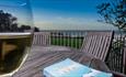 Glass of wine and book on the outside dining tables with sea views at Beach Cottage, Fort Victoria Cottages, Yarmouth, Isle of Wight, self catering