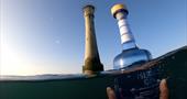 A picture of the blue Atlantic Strength bottle next to Bishop Rock Lighthouse