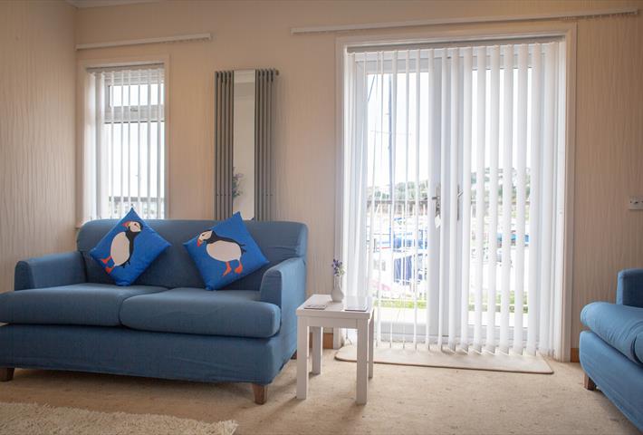Blue sofa in a lounge in front of a window and patio doors