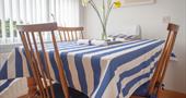 Daffodils on top of a four seater dining table with white and blue striped tablecloth
