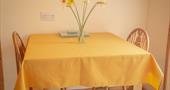 Daffodils on a 2 seater dining table with yellow table cloth