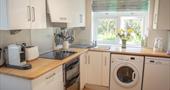 A white kitchen and appliances with a wooden worktop