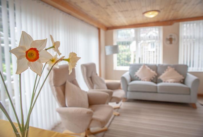 Lounge with sofa, two arm chairs and daffodils on a table