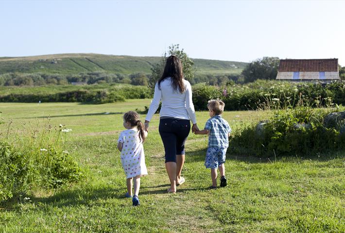 Mother and two children walking in a field at Hell Bay Hotel