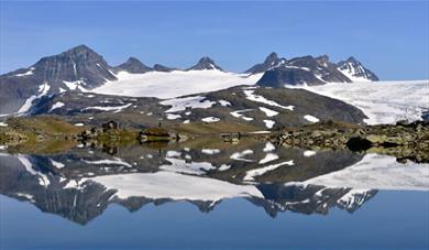 Smørstabbtindane seen with clear water in front at Sognefjellet. 