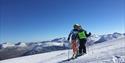 Bilde fra bakken med to skiløpere. strålende sol, blå himmel. Galdhøpiggen sommerskisenter, Galdhøpiggen summer skiing center, juvass