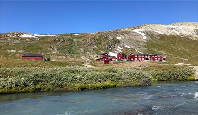 Blue river flows past Krossbu tourist cabin in the summer. 