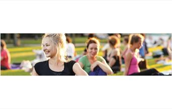 ladies sat outside in the sun doing yoga