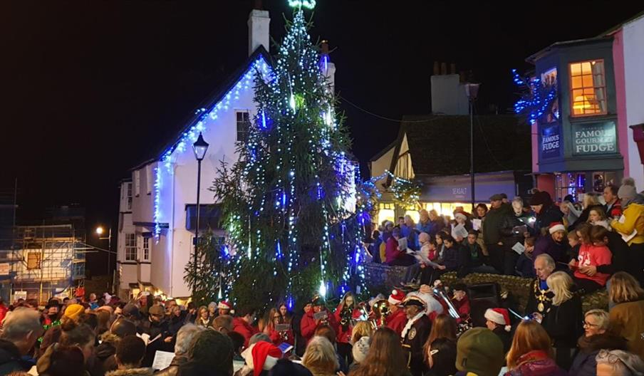 People singing carols around a Christmas tree in Lyme Regis