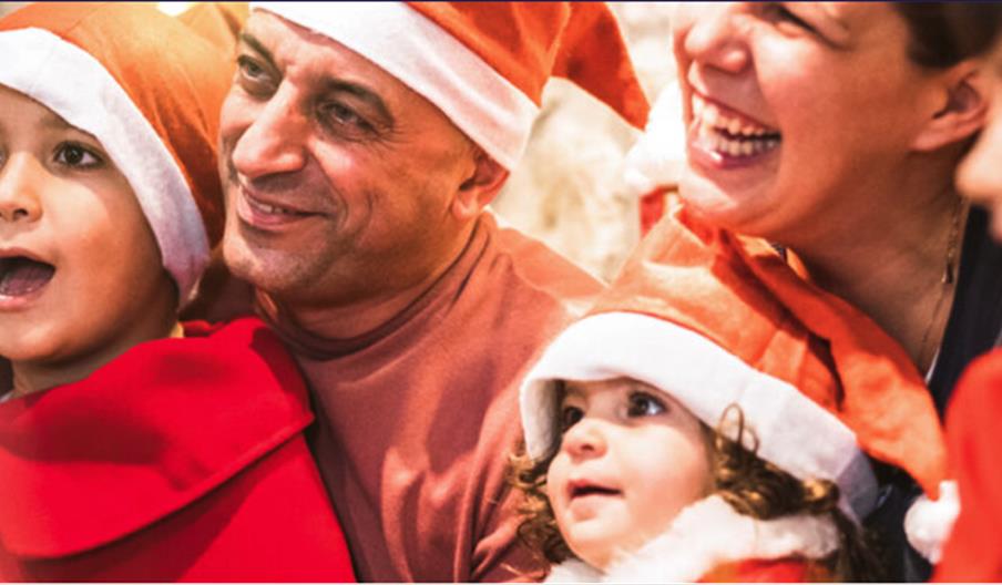 An image of families in Christmas costumes watching an event