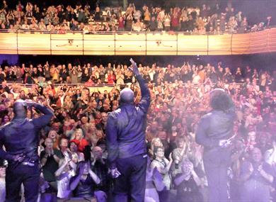 The performers are interacting with their fans in a full theatre of adoring fans.