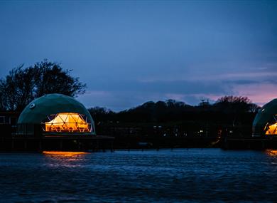 Nighttime view of the pods from across the river.