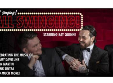 Ray and the band sat on red theatre chairs in formal dress.