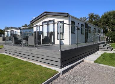 Caravan with grey decking and glass fence