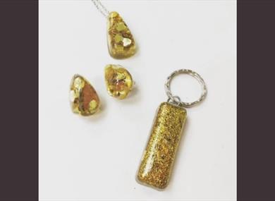 Three pieces of jewellery - a necklace, earrings and a keyring with a yellow colour.