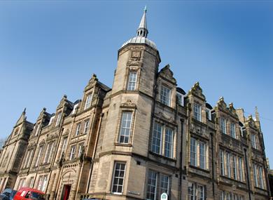 The Grade Two listed Storey building made of sand coloured stone with tall Georgian windows, and a tower with spire.