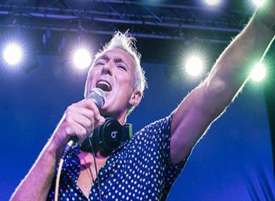 Martin Kemp, under the lights with a microphone addressing the audience.