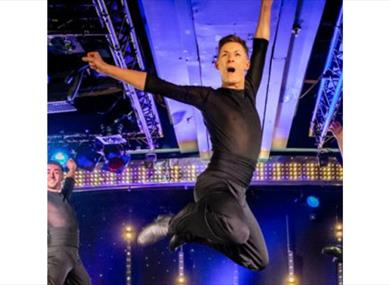 A dancer leaps in the air entertaining the audience on stage.